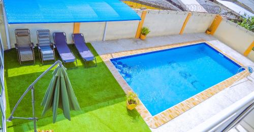 an overhead view of a swimming pool with chairs and an umbrella at Pool House Retreat in Accra in Accra