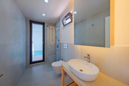 a bathroom with a sink and a toilet and a window at Villa Neo with 2 private pools, bbq, jacuzzi and sauna in Fethiye