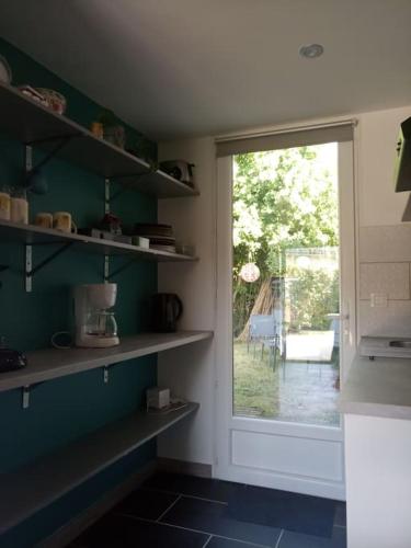 une cuisine avec des étagères et une porte donnant sur une terrasse. dans l'établissement Petite maison avec jardin entre lac et village, à Hourtin