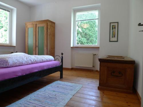 a bedroom with a bed and a dresser and two windows at Das Alte Forsthaus in Geisenheim