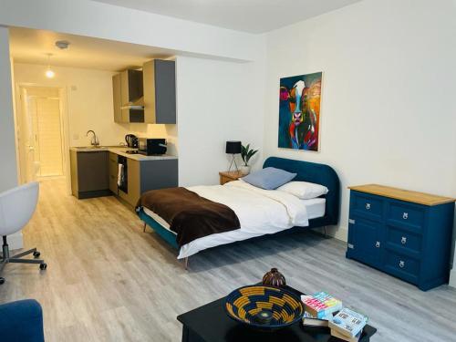 a bedroom with a bed and a desk and a kitchen at Beautiful Central Woking Studio in Woking