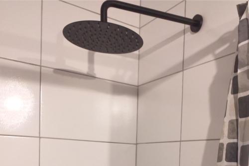 a shower head in a bathroom with white tiles at Chakana Family Home Lima Airport in Lima