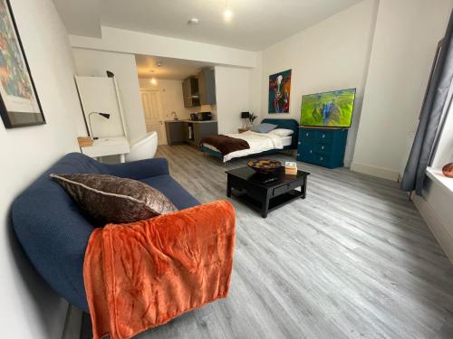 a living room with a blue couch and a bed at Beautiful Central Woking Studio in Woking