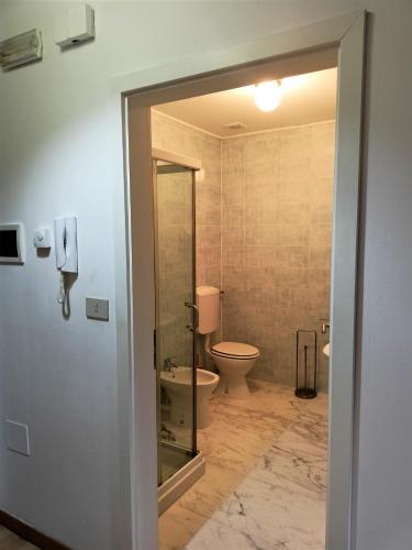 a bathroom with a toilet and a glass door at Tenuta PARAVANO in Povoletto