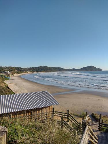 a view of a beach with a building and the ocean at Suítes do Vale - Praia do Rosa in Imbituba