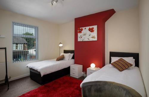 a bedroom with two beds and a red wall at Vicarage House in Blackpool
