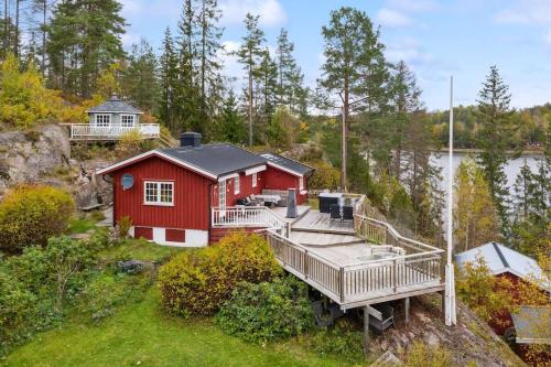 ein rotes Haus mit einer Terrasse neben einem Wasserkörper in der Unterkunft Familievennlig hytte ved populært badevann! in Sandefjord