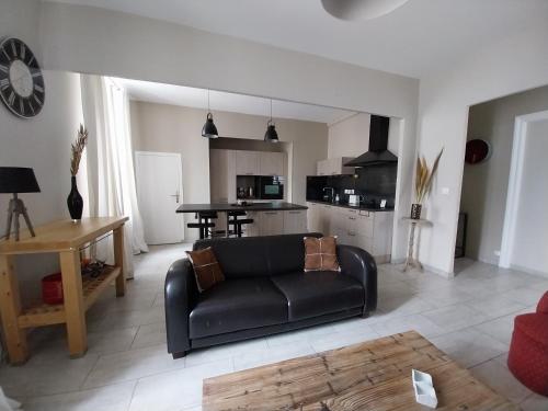un salon avec un canapé noir et une cuisine dans l'établissement My sweet home, à Carcassonne