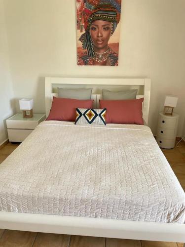 a white bed with red pillows and a painting on the wall at BluePalm case in Petit-Bourg