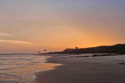 um pôr-do-sol numa praia com o oceano em Anne’s Beach House em Nyanyanu