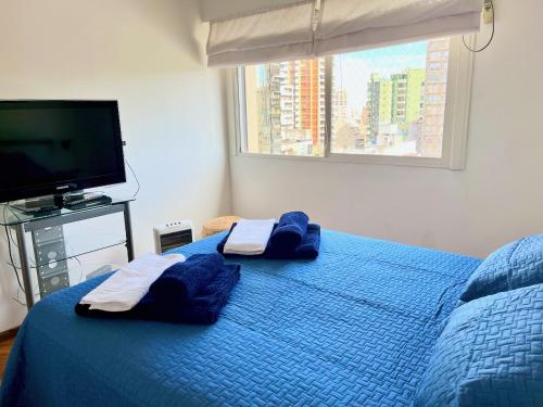 1 dormitorio con 1 cama azul con almohadas azules y TV en Excelente y Luminoso Palermo Soho / Botanico 2 amb en Buenos Aires