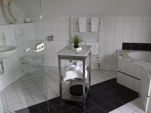 a white tiled bathroom with a sink and a toilet at Hotel Kleiner König in Schwangau