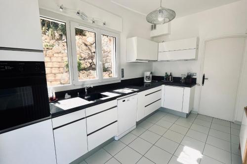 une cuisine avec des armoires blanches et des comptoirs noirs dans l'établissement Rare pearl with pool and sea view, à Mandelieu-la-Napoule