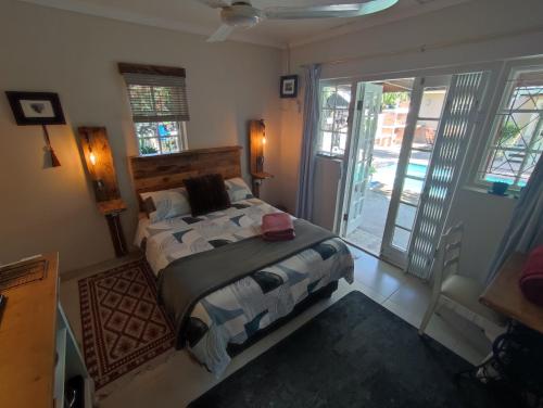 a bedroom with a bed in a room with windows at Paradise in the City Cottage Two in Port Elizabeth