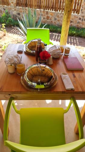 a wooden table with a green chair at a table at Olive Country Lodge - Eswatini in Ngwempisi