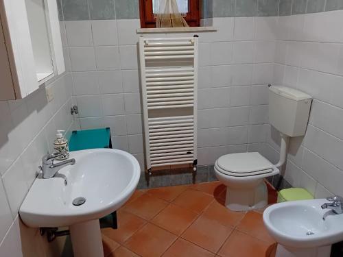 La salle de bains est pourvue d'un lavabo blanc et de toilettes. dans l'établissement Appartamento Il Castagno, à Fosdinovo