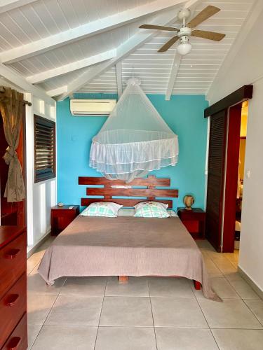 a bedroom with a bed with a ceiling fan at Case Coco Pointe Batterie. Piscine, vue mer, 4 p. in Deshaies