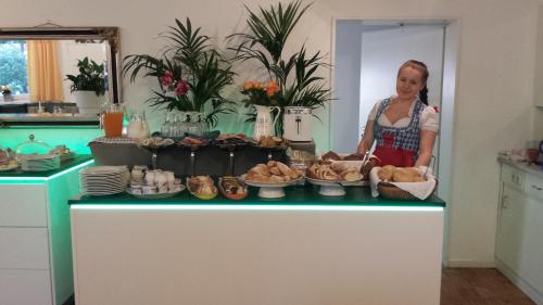 a woman standing in a kitchen with a table of food at Hotel Kleiner König in Schwangau