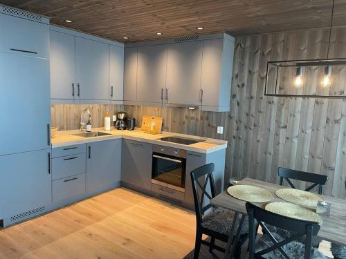 a kitchen with blue cabinets and a table and chairs at Ski in/out, amazing views, 3 bedrooms in Noresund