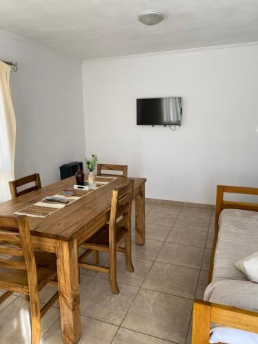 a dining room with a wooden table and a couch at Complejo Pampa 2 in Santa Rosa