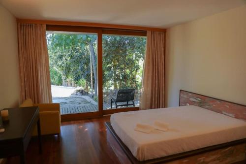 um quarto com uma cama e uma grande janela em Quintinha das Laranjeiras em Santa Cruz do Douro