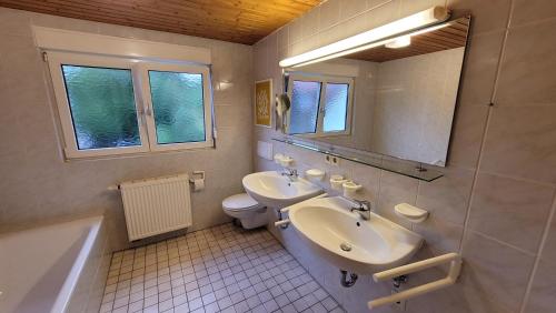 uma casa de banho com 2 lavatórios, um WC e um espelho. em Gästehaus Huber Meersburg em Meersburg