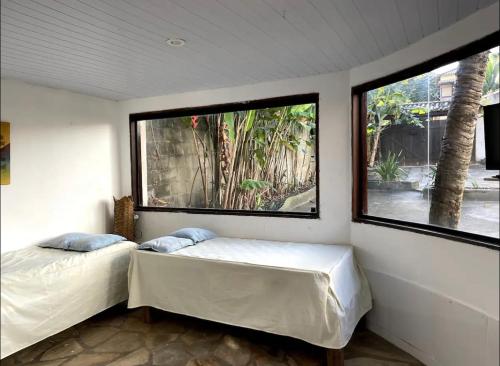 1 Schlafzimmer mit 2 Betten und 2 großen Fenstern in der Unterkunft Casa Flamboyant Buzios in Búzios