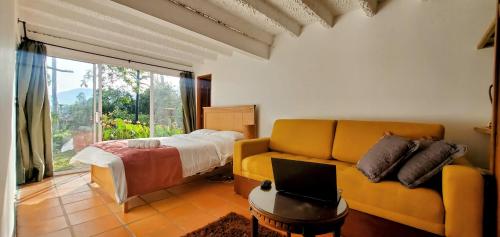 Hotel El Gran Chaparral في كالاركا: غرفة معيشة مع أريكة وسرير