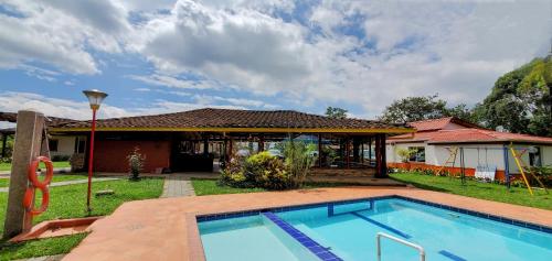 a swimming pool in front of a house at Hotel El Gran Chaparral in Calarcá