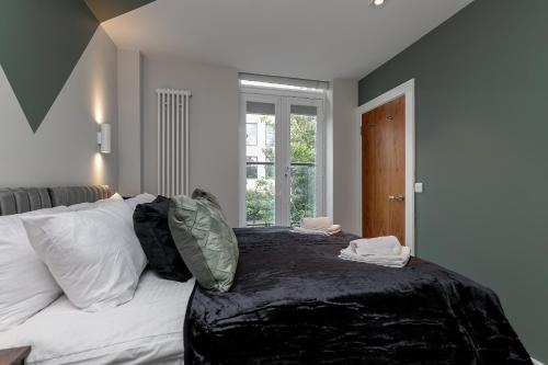 um quarto com uma cama com lençóis brancos e uma janela em MK CITY CENTRE, THE DIAMOND SUITE, FREE Parking Space, PREMIUM SPACIOUS Apartment with FOOSBALL TABLE em Milton Keynes