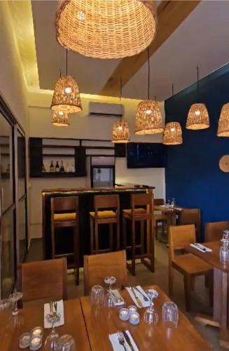 a dining room with tables and chairs and chandeliers at Nandy's home in Odza II