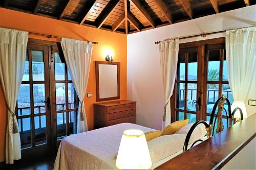 a bedroom with a bed with a mirror and windows at Casa La Molina Spa in Triquivijate