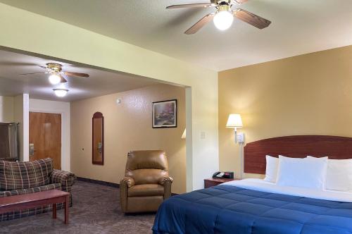 um quarto de hotel com uma cama e uma cadeira em Candlelight Inn & Suites Hwy 69 near McAlester em McAlester