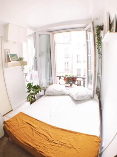 un lit dans une chambre avec une grande fenêtre dans l'établissement Green cozy studio au cœur de Paris, à Paris