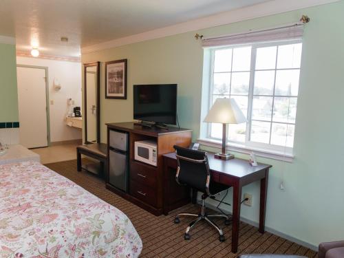 Cette chambre comprend un lit, un bureau et une télévision. dans l'établissement Sweet Home Inn, à Sweet Home