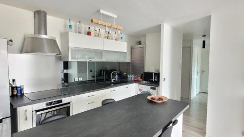 een keuken met witte kasten en een zwart aanrecht bij Cosy Home Paris in Carrières-sous-Poissy