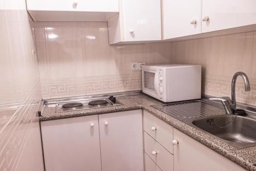 a small kitchen with a sink and a microwave at Hotel Tàrbena in Tárbena