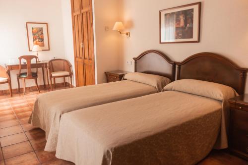 a hotel room with two beds and a table at Hotel Tàrbena in Tárbena