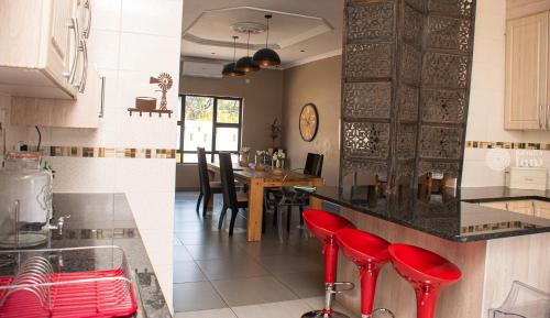 dos fotos de una cocina con taburetes rojos. en Kendi's Inn Self Catering Apartments, en Jwaneng