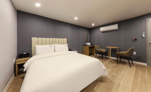 a bedroom with a white bed and a table and chairs at Hotel Laon in Tongyeong