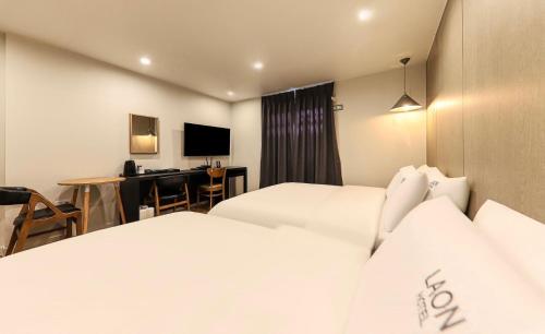 a hotel room with two beds and a desk at Hotel Laon in Tongyeong