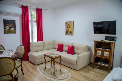 a living room with a white couch and red curtains at Apartman Centar in Sremski Karlovci