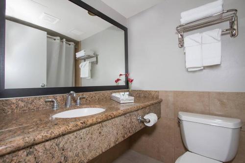 a bathroom with a sink and a toilet and a mirror at Modern studio Across From Hilton lagoon beach PW920 in Honolulu