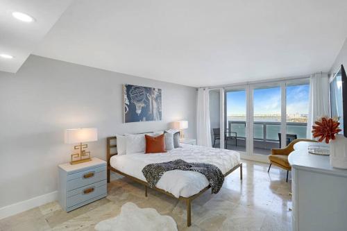 a white bedroom with a bed and a large window at The Audrey! Penthouse With Direct Water Views! in Miami