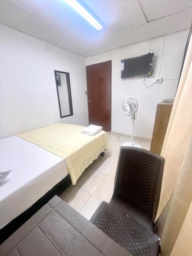 a room with a bed and a chair and a fan at Casa Santiago Mayor in Cali
