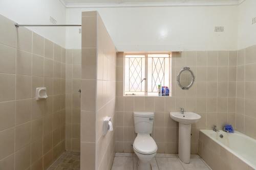 a bathroom with a toilet and a sink and a tub at Wood Road Guest Lodge in Victoria Falls