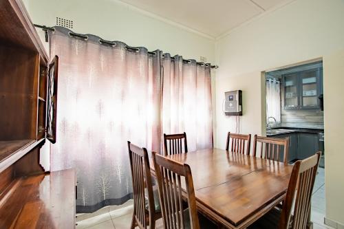 a dining room with a wooden table and chairs at Wood Road Guest Lodge in Victoria Falls