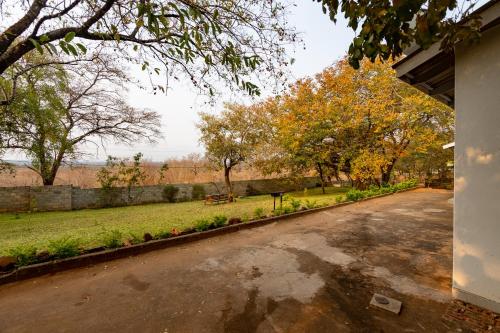 an empty street in a park with trees and a wall at Wood Road Guest Lodge in Victoria Falls