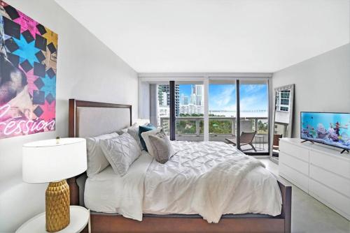 a white bedroom with a bed and a television at Shore to Please! Park And Water Views! in Miami