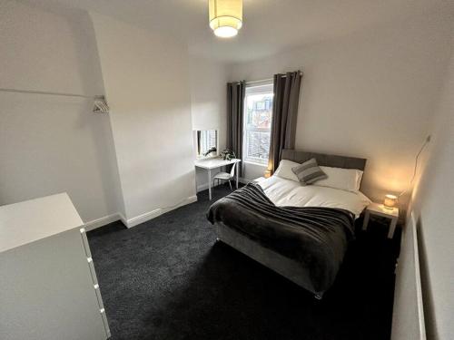 a bedroom with a bed and a desk and a window at Bright Home From Home in Stoke on Trent